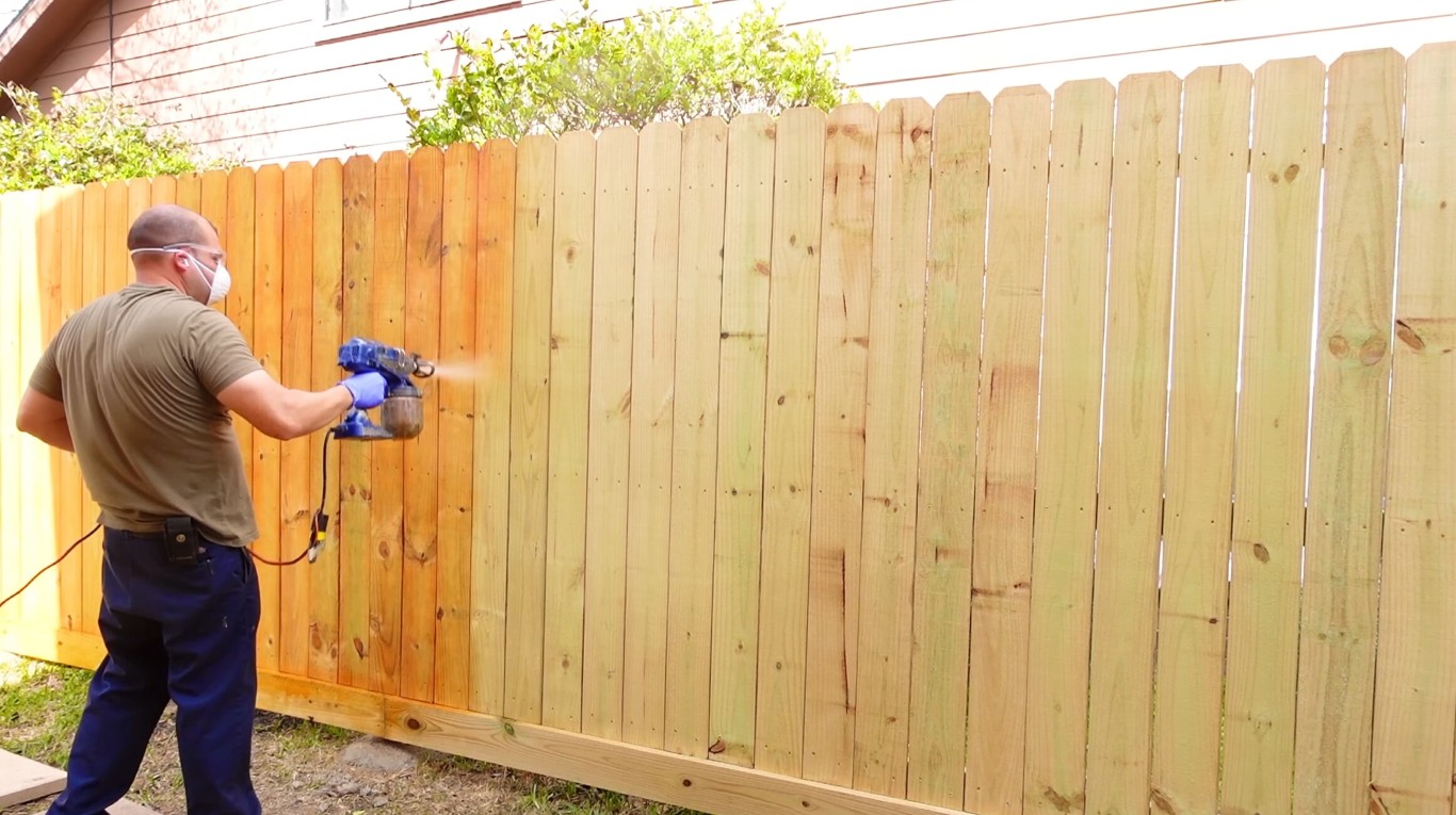 Professional fence contractor staining and maintaining wood fence in Delano, CA